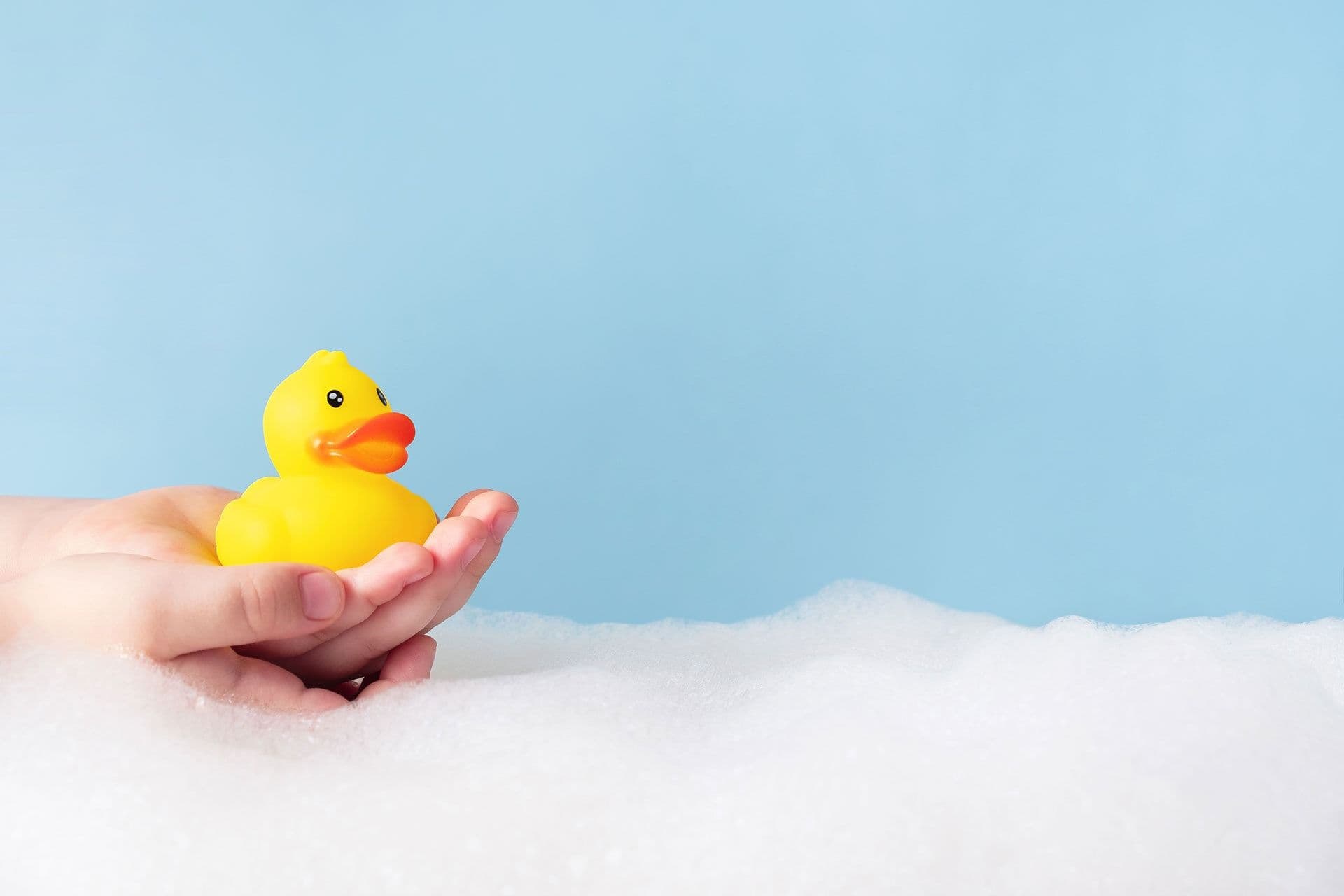 child hands holding yellow rubber duck