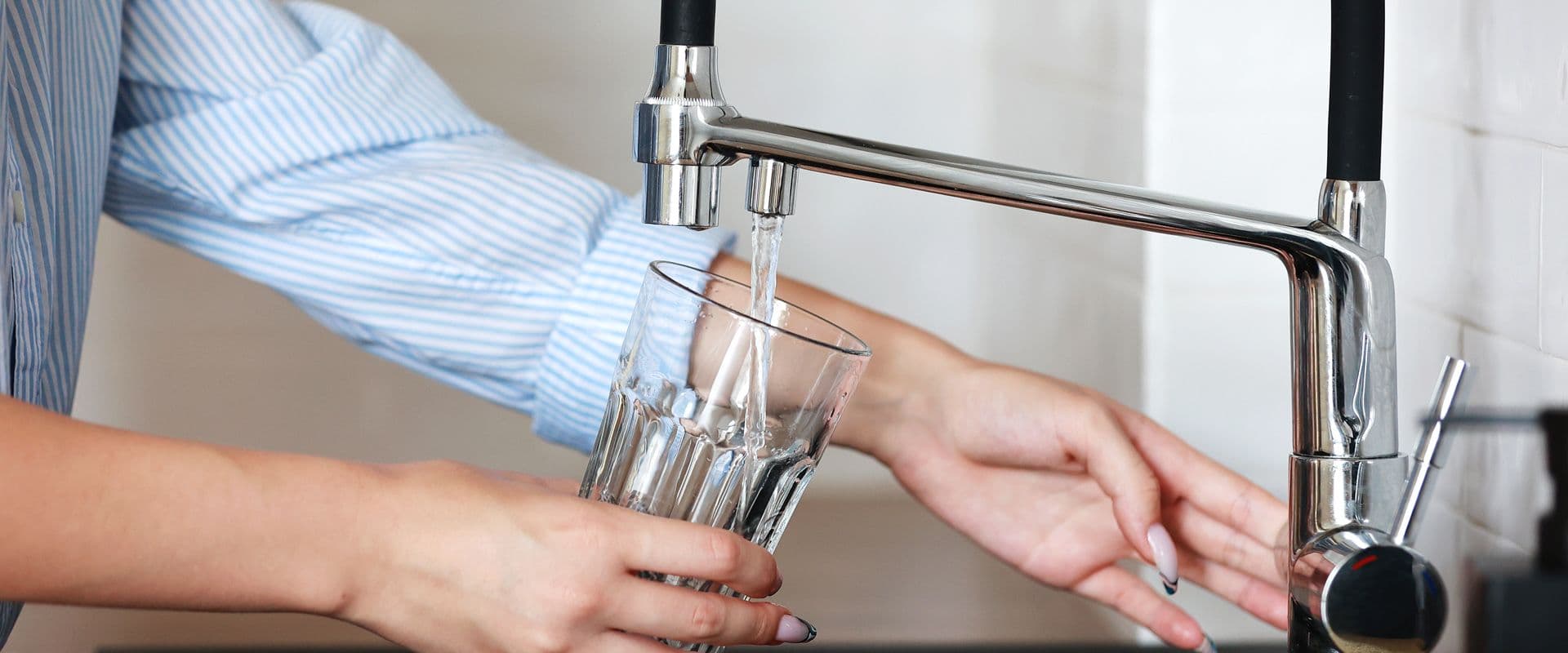 A person fills a glass with tap water.