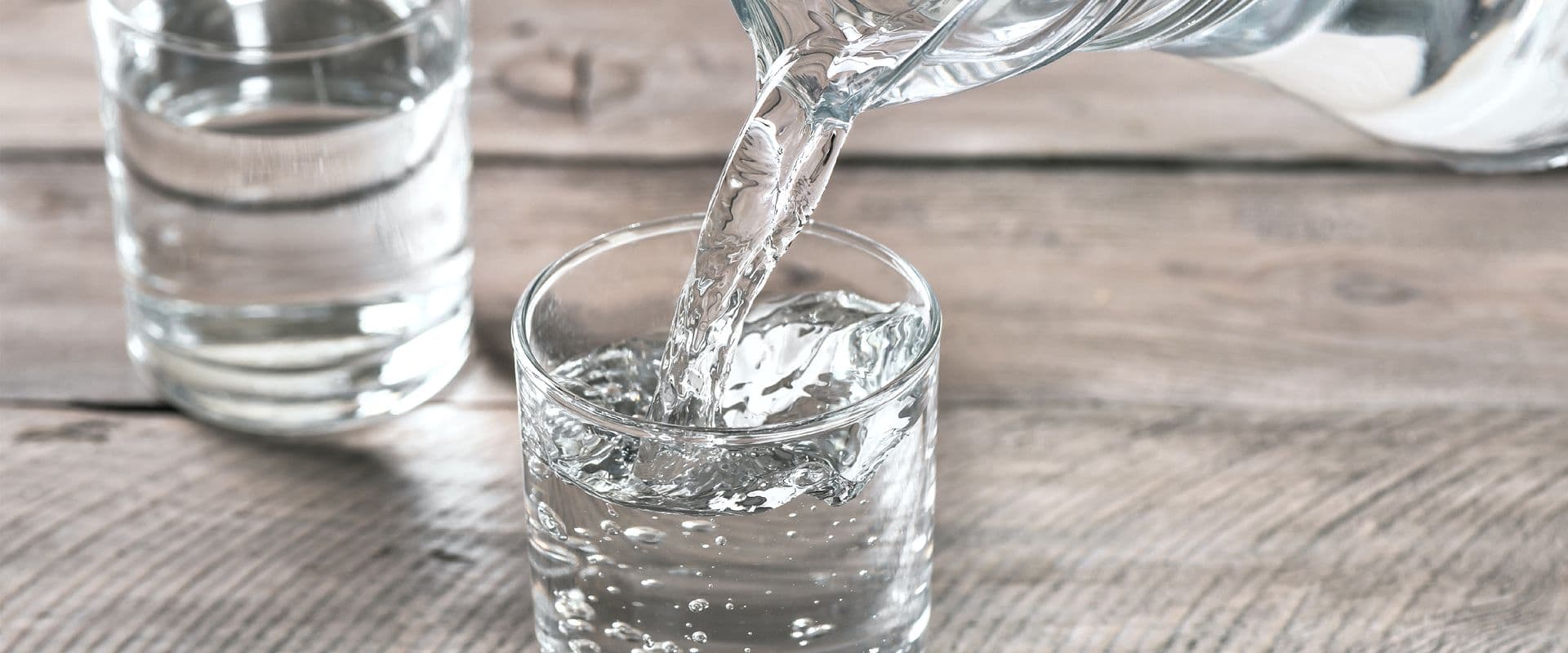 Water is poured from a pitcher into a glass.