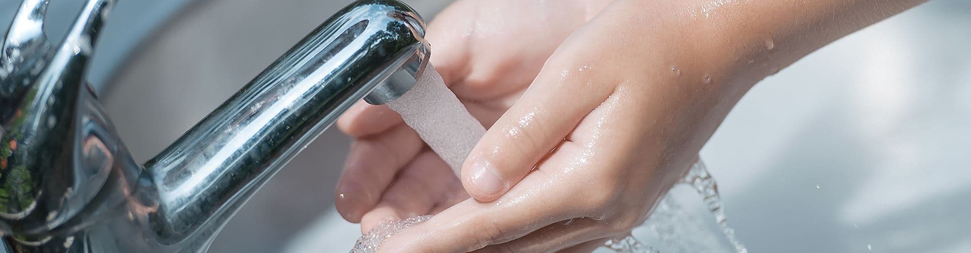 Hands under a running faucet.