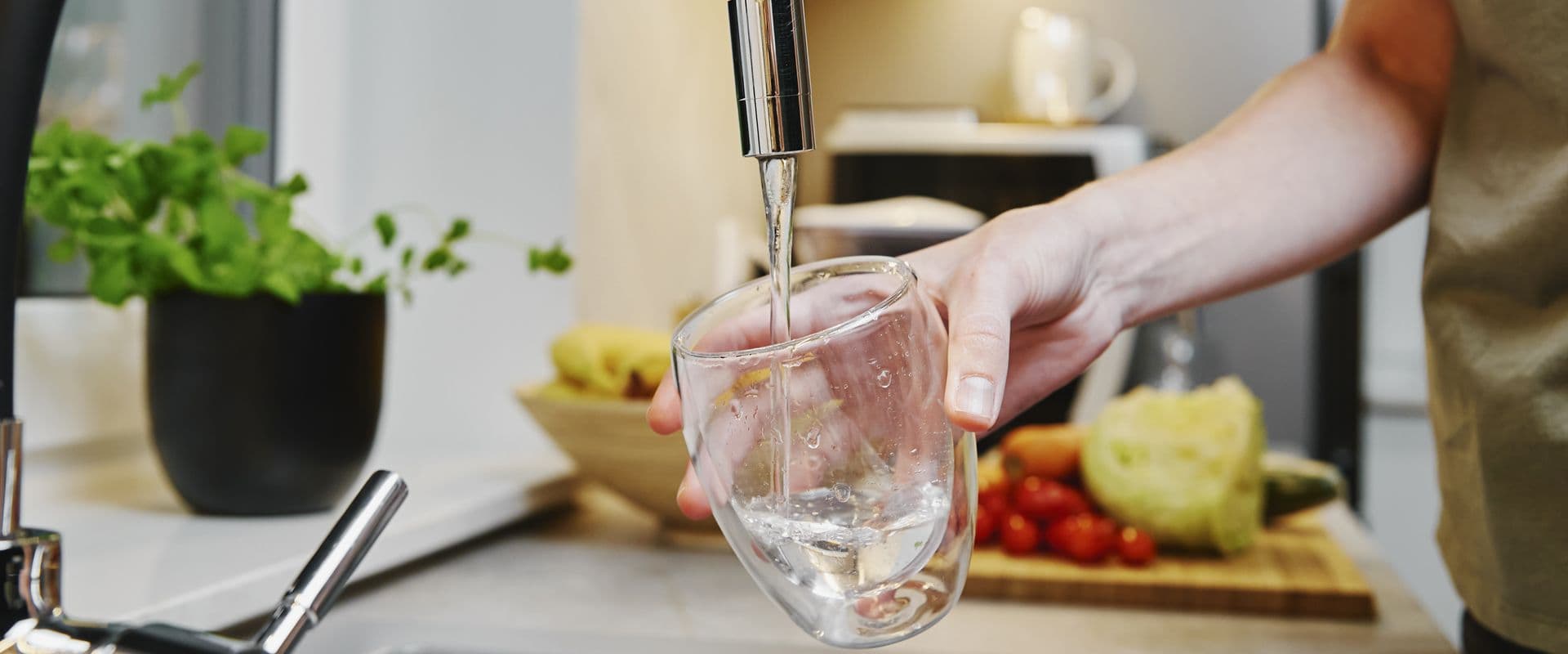 A person fills a glass from a sink.