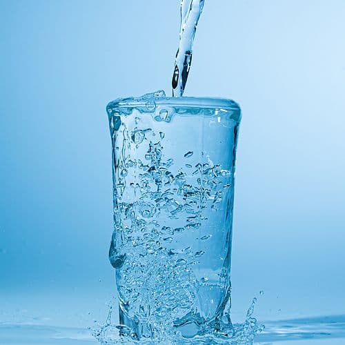 Water overflows from a glass as it is poured.